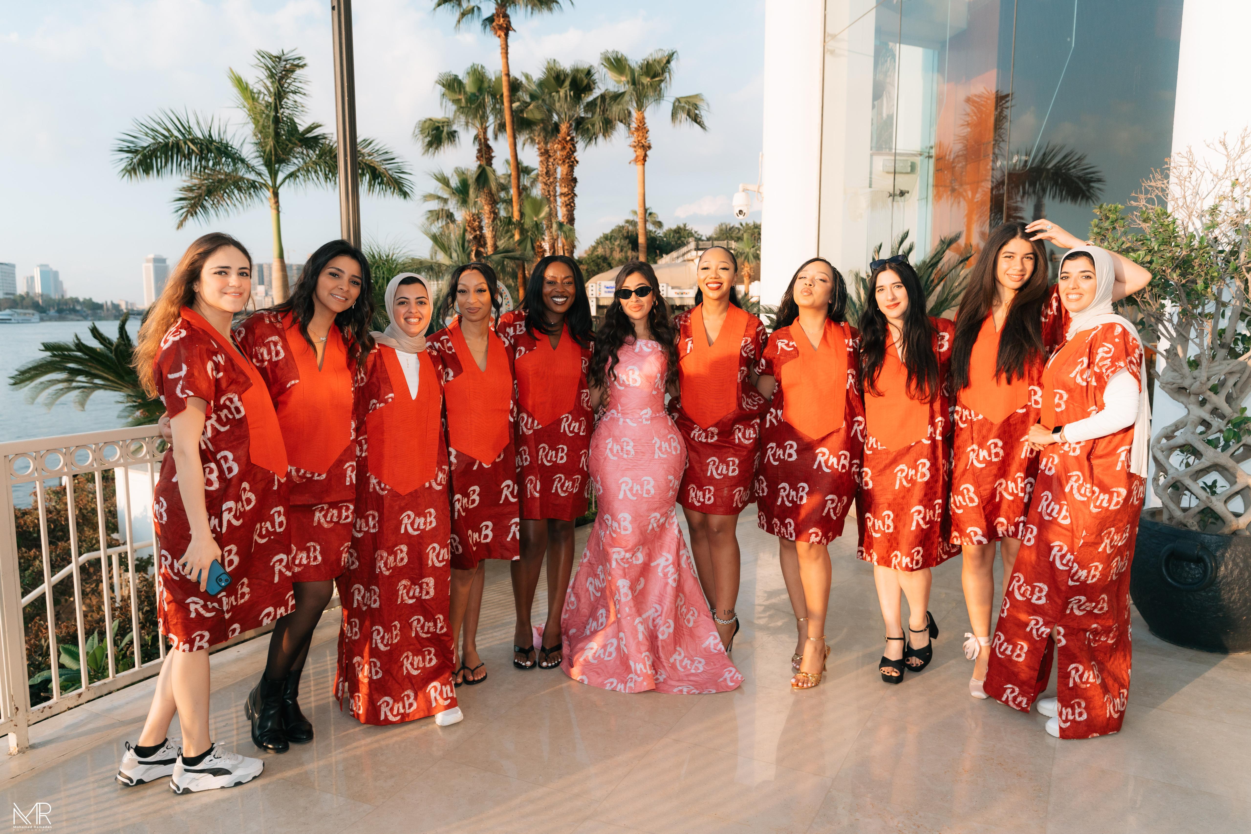 Bride in pink RnB gown surrounded by bridesmaids in matching red bubus