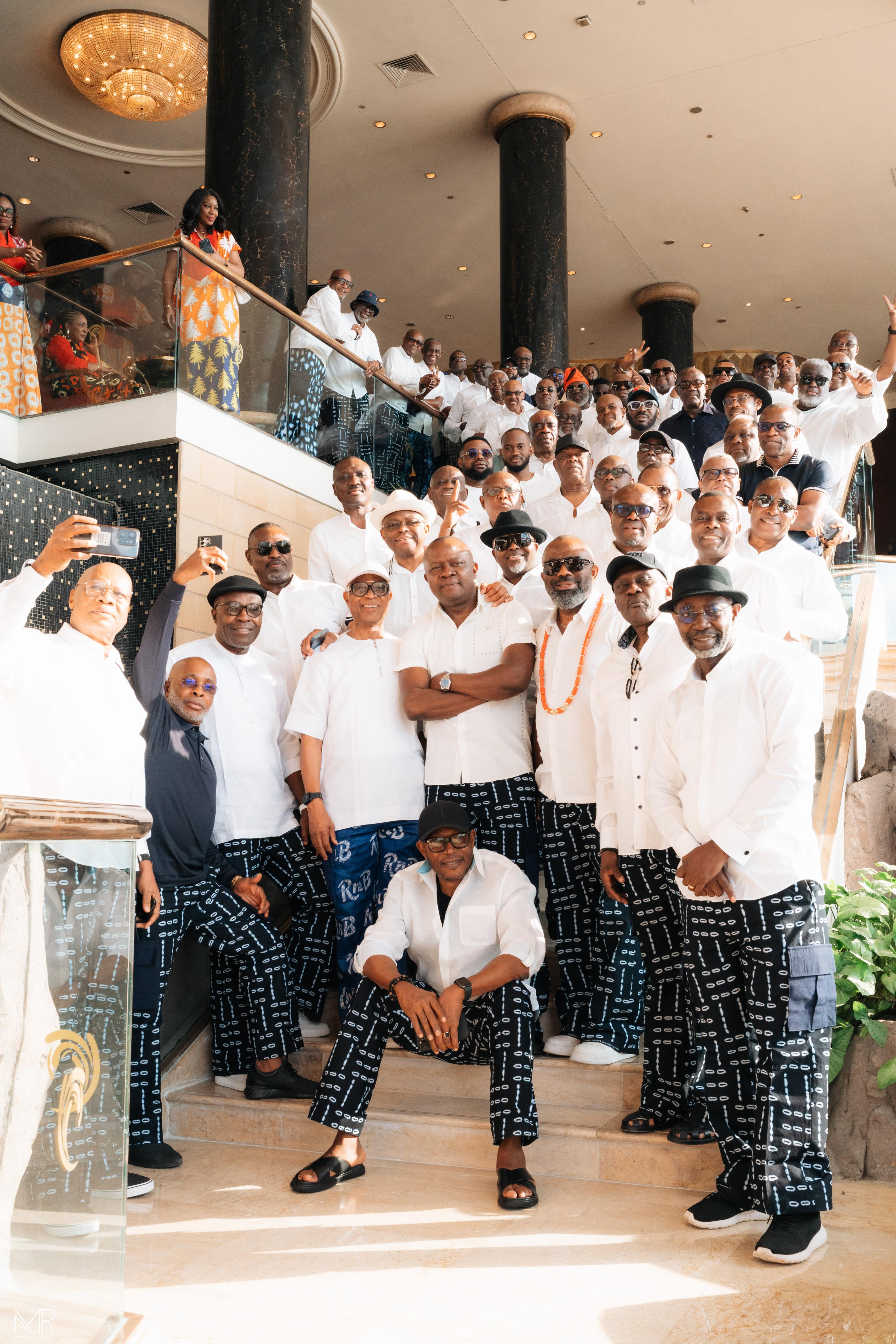 Large group of men in white tops and patterned trousers on staircase